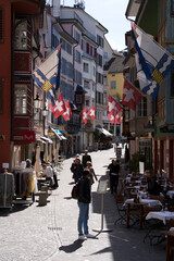 Old medieval alley with beautiful oriels named Augustinergasse at the old town of Zurich with Swiss flags on both sides. Photo taken May 8th, 2021, Zurich, Switzerland.
