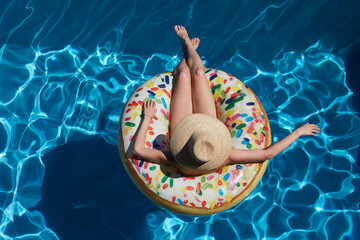 Young woman on inflatable donut ring in pool