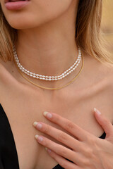 Close-up of a beautiful young blonde woman's neck  with gold earrings and pearl,  gold and diamonds necklaces