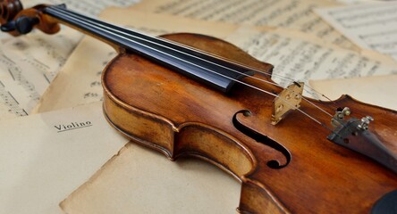 An old antique violin on a table with yellowed sheet music close-up.  © Irina