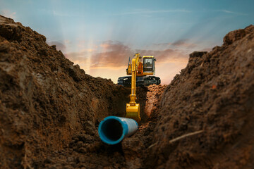 Excavator is digging in the construction site pipeline work on sunset sky background - obrazy, fototapety, plakaty