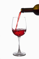 Red wine is poured into a glass from a bottle, isolate on a white background