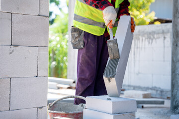 bricklayer builder using cement mortar to put the Lightweight bricks. at construction site