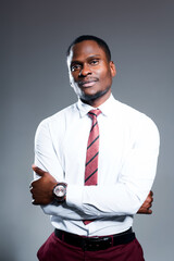 Serious african american man in shirt and tie folds his arms over his chest and stands against gray background