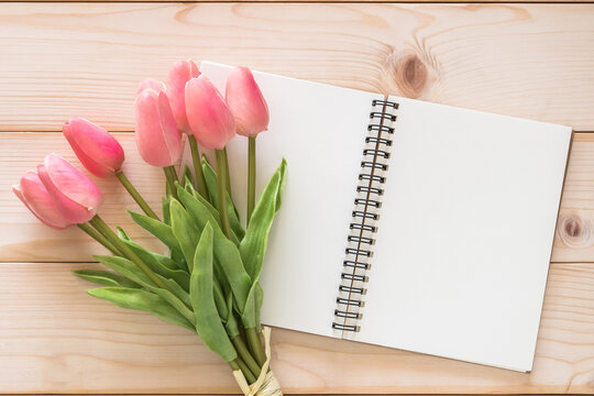 Tulip flower with white blank note book page background on white wood backdrop for mother’s day holiday card and spring seasonal greeting celebration
