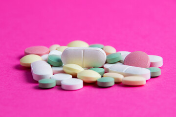 Obraz na płótnie Canvas Many multicolored vitamins and pills on a pink background copy space, close-up
