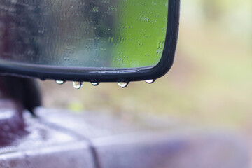 Car side mirror in the rain in water drops