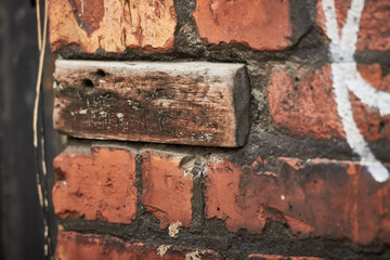 Wooden block replacing brick in wall closeup