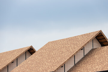 brown asphalt roof shingle background with blue sky.