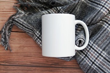 White coffee mug mockup on dark wooden background and cozy blanket, cup mock up for autumn or winter design.