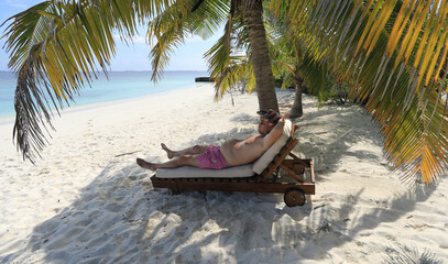 Fototapeta na wymiar a man on a sunbed on the shore of a tropical island