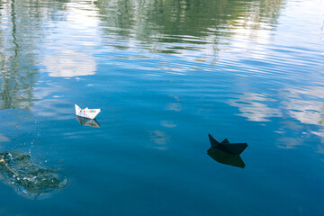 Black and white paper skiffs float on water