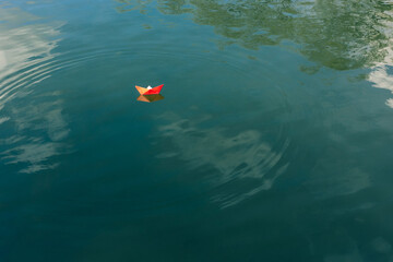 Red paper boat floats on the river