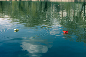 Red and white paper boats float on the water