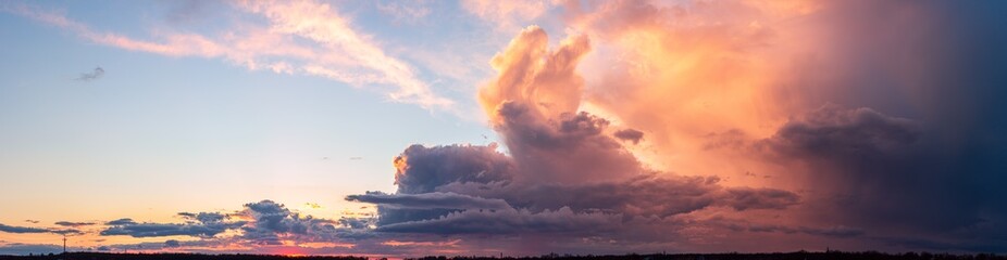 Fototapeta premium A bright fabulous and intense sunset with large clouds. Rainy sky at the end of the day