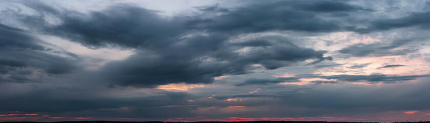 Fototapeta premium Dark sunset with gloomy clouds and red light on the horizon