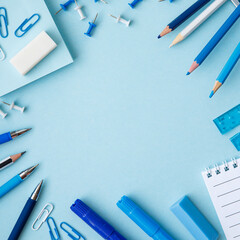 Frame of white and blue school supplies on an bright blue background. Concept back to school. School or stationery shop spring summer sea concept. Copy space, flat lay, top view, background.