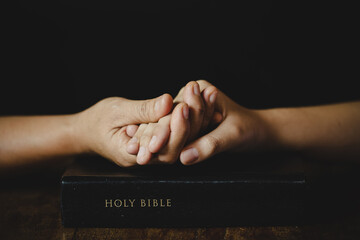 Hands folded in prayer on a Holy Bible