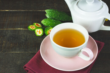 Bitter gourd or bitter melon tea in ceramic cup on wooden background. Scientific name is Momordica charantia. As a whole food and herbs for treating diseases.