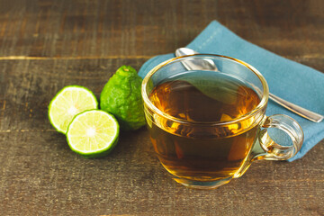 Bergamot tea or Earl Grey tea in transparent cup and fresh bergamot fruit with sliced on wooden table.