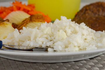Brazilian food dish with steak and rice and carrot and cassava with eye