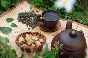 Obraz na płótnie Canvas Tea in nature. Dry and brewed green tea on a bamboo napkin. It also has mint leaves and cane sugar cubes.