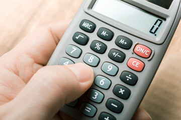 Finger Touching A Calculator With Coins In Background - Accounting Concept
