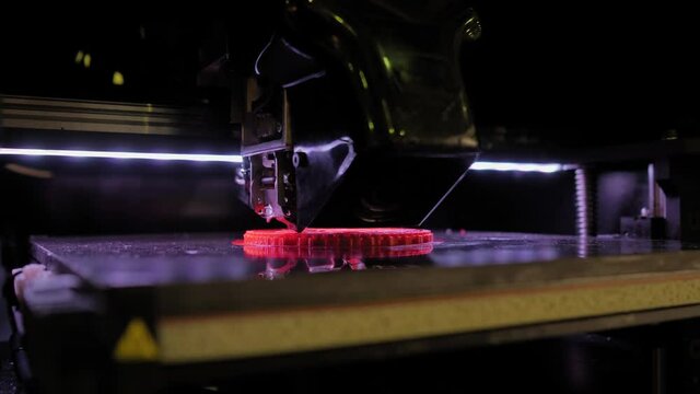 Automatic three dimensional printer machine printing red flat plastic model at modern technology exhibition - close up. 3D printing, futuristic, prototype, manufacturing and production concept