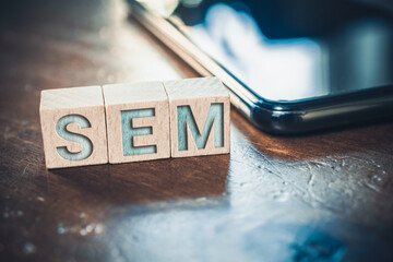 SEM Search Engine Marketing Written On Wooden Blocks Next To A Smartphone On A Table