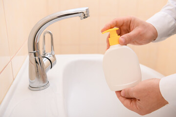 hand washing with soap or gel under running water in the washbasin, cleanliness and hygiene, men's hands dressed in a white shirt
