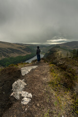Man standing on his back on top of mountain with lake in background at Glendalough Wicklow