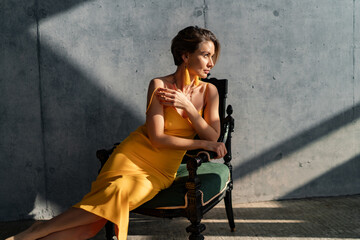 attractive woman in yellow summer dress in interior room concrete wall background