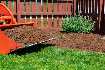 Tractor loader with wood chips or mulch and flowerbed. Lawncare, gardening and backyard landscaping...