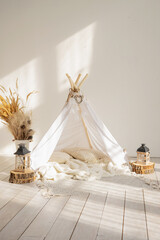 White fabric kids teepee and Native American decor in a children's room on a sunny day.