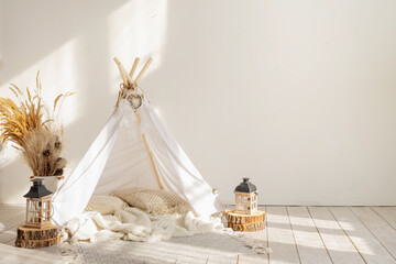 White fabric kids teepee and Native American decor in the interior of the children's room with copy...