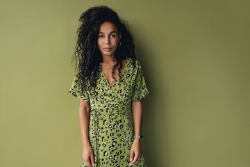 attractive black african american woman posing in stylish green dress isolated on green background