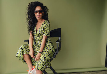 attractive black african american woman posing in stylish green dress isolated on green background