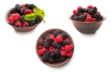 Raspberry, blackberry and mint leaf in ceramic brown bowl isolated on white