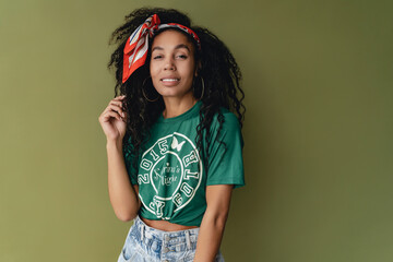attractive black african american woman posing in stylish hipster outfit on green background