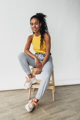 attractive black african american woman posing in stylish hipster outfit on white background