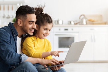 Online Shopping Concept. Happy Arab Dad And Little Daughter Using Laptop Together