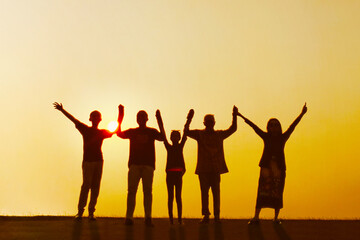 Three generation family standing with raised hands