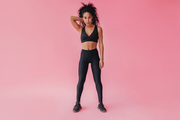 Fototapeta na wymiar attractive black african american woman in black leggins fitness outfit on pink background