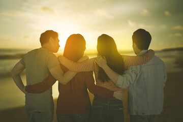 Group of young people embrace each other on beach