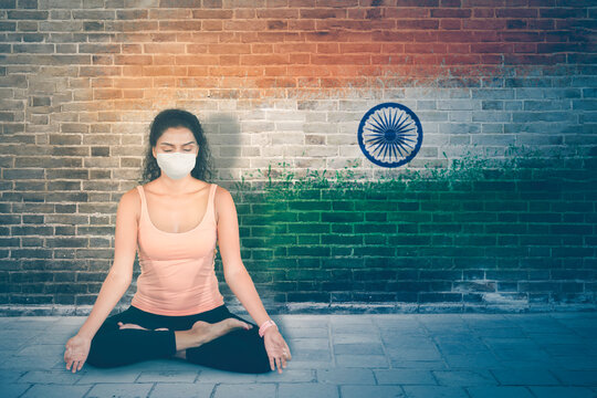 Woman in face mask exercising yoga with India flag