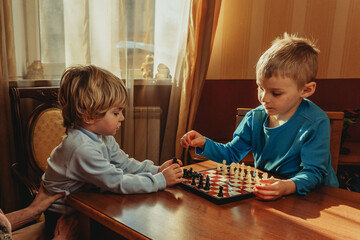Two brothers learning play chess in the room