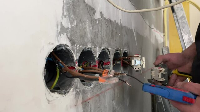  The electrician prepares with wire stripper plier prepares  electricial wires for the installation of the socket in a residential electrical system. Construction industry.