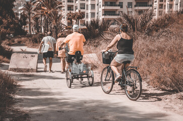 Retired couples on vacation, walking and riding bikes on the way back home from the beach on a sunny summer day. - Powered by Adobe