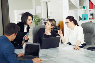 Fototapeta premium Three young successful business women in the office working together on a project