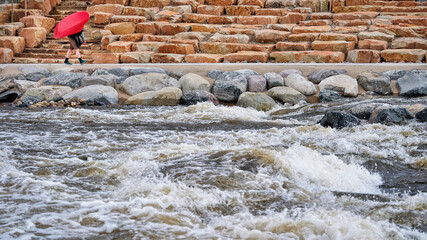 kayaker is carrying his kayak upstream in the Poudre River Whitewater Park, Fort Collins in...